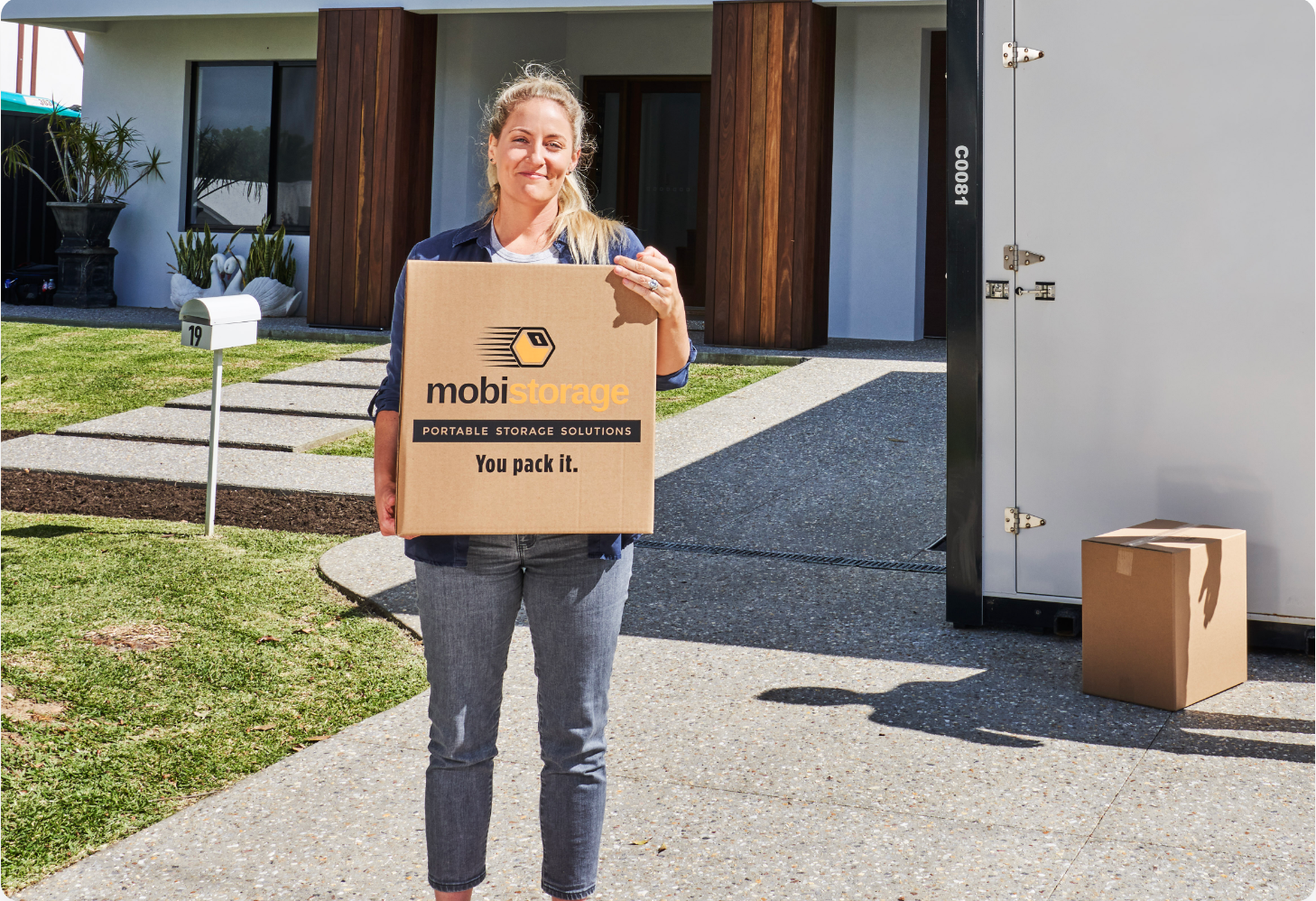 3-1056-0147-optimized A woman carrying a mobistorage brown box