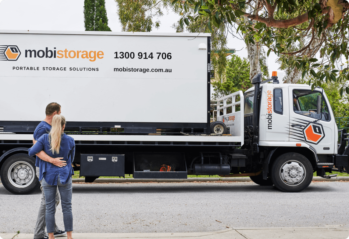 MOBI_Couple_Waving_Truck_0860@2x man and women standing in front of mobile storage container